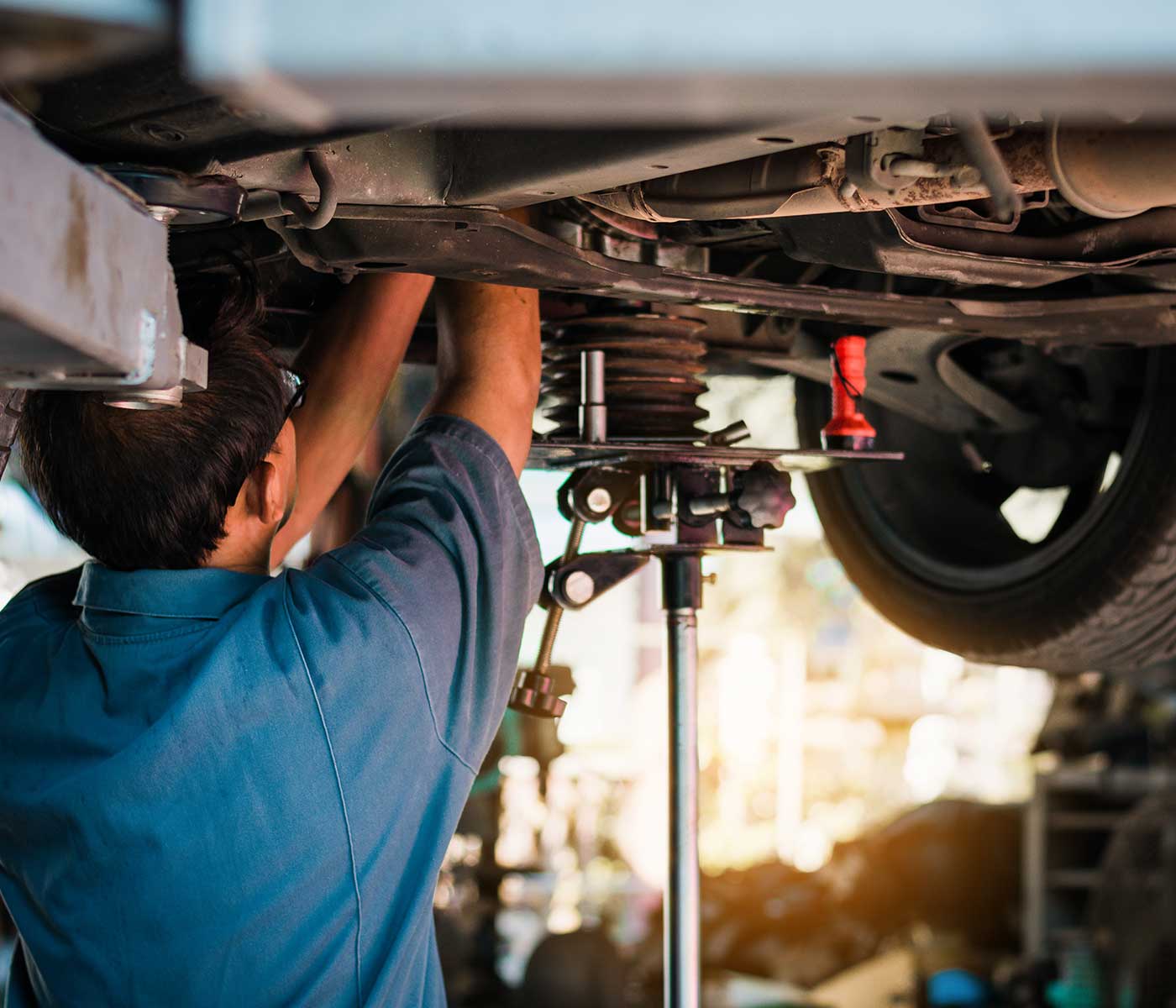 Mechanic inspects car suspension system and chassis