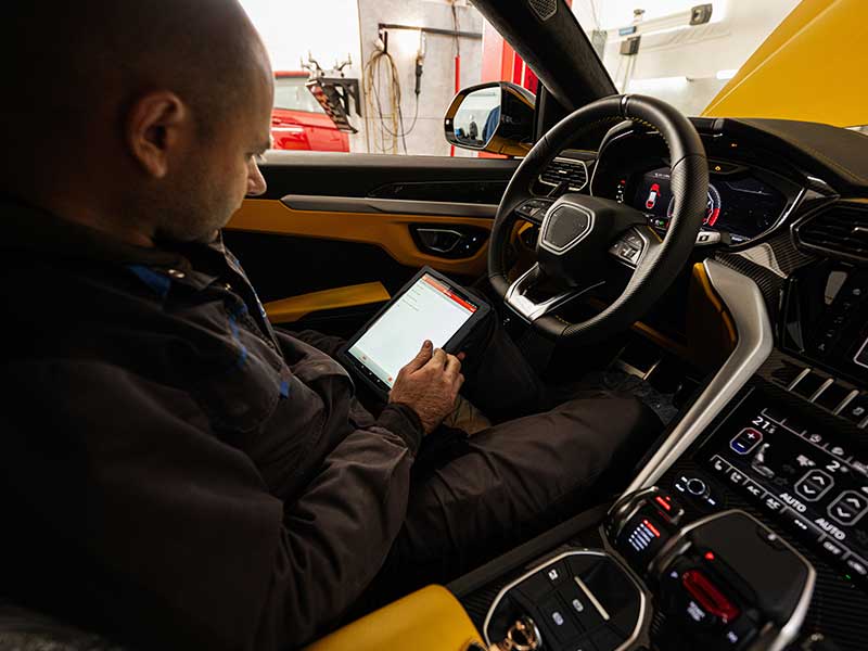 Mechanic using digital tablet, while sitting in yellow sport car suv