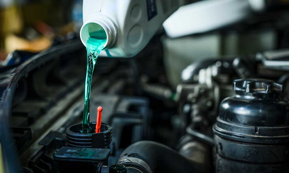 mechanic pouring engine coolant fluid into radiator fill hole
